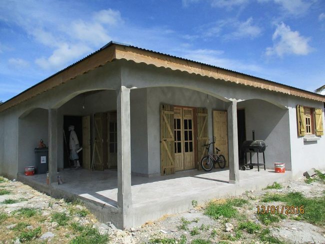 Maison de plain-pied en travaux avec terrasse couverte et menuiseries en bois